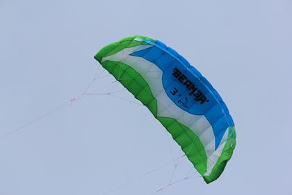 Kitesurf-Schirm in Blau und Grün am Himmel über der jütländischen Küste