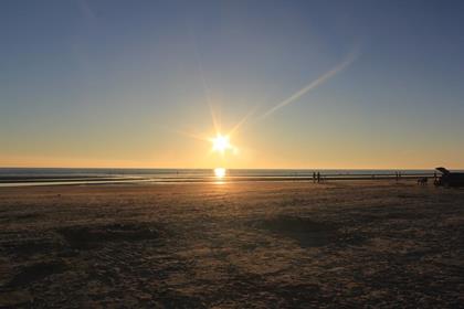 Sonnenuntergang über dem Meer an einem Sandstrand der Nordseeküste