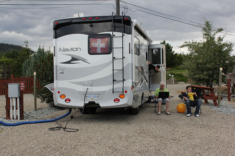 Familie sitzt vor dem Wohnmobil auf dem Campingplatz in Kelowna