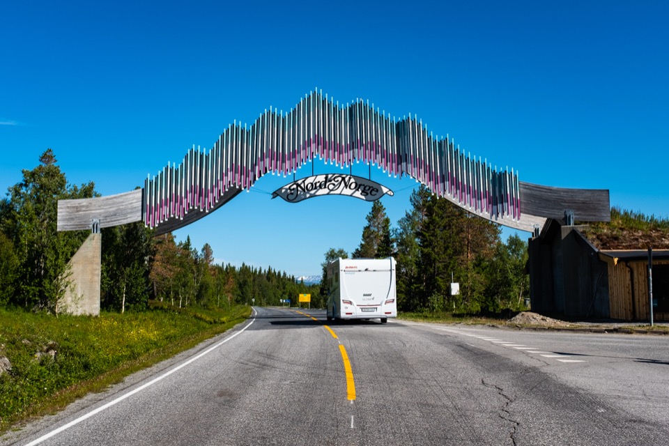 Camper fährt unter dem Nord-Norge-Torbogen über der Strasse hindurch
