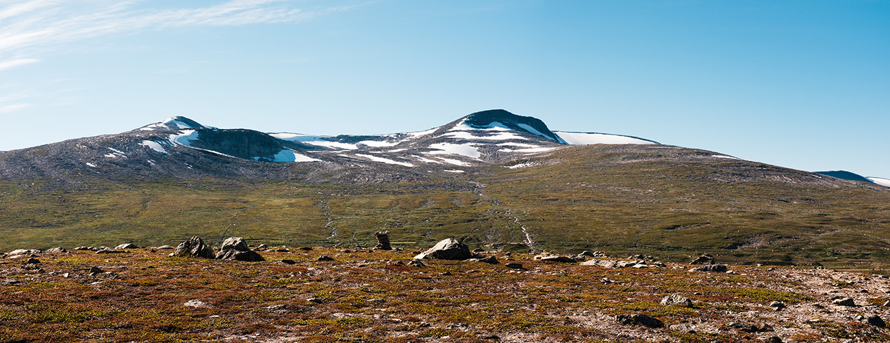 Weite, karge Hochebene des Saltfjell mit schneebedeckten Bergen im Hintergrund