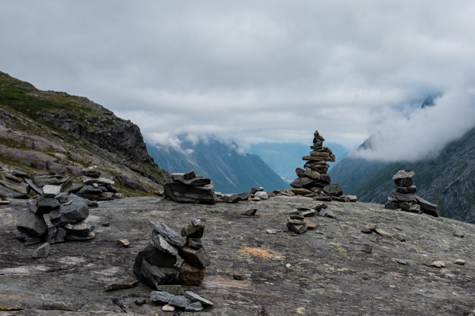 Steinmännchen auf einem Aussichtspunkt beim Trollstigen, im Hintergrund Wolken über dem Tal