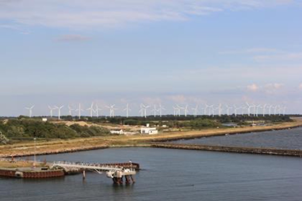 Windräder entlang der norddeutschen Küste, im Vordergrund ein Kanal mit Steg