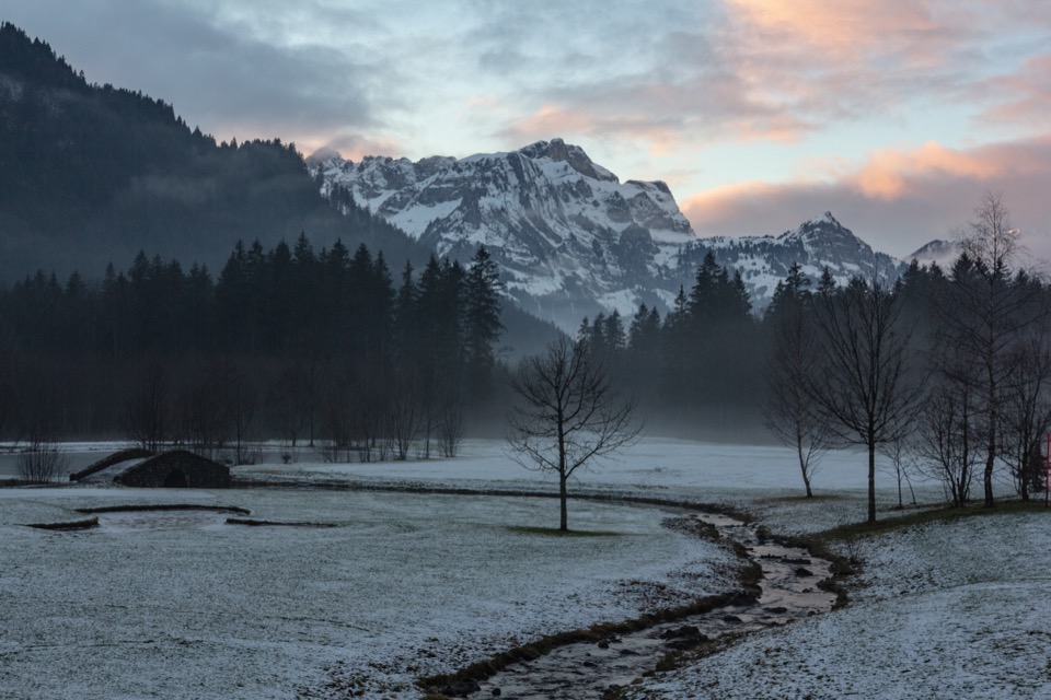 Nebliges Tal in der Morgendämmerung mit rosa angeleuchtetem Gipfel